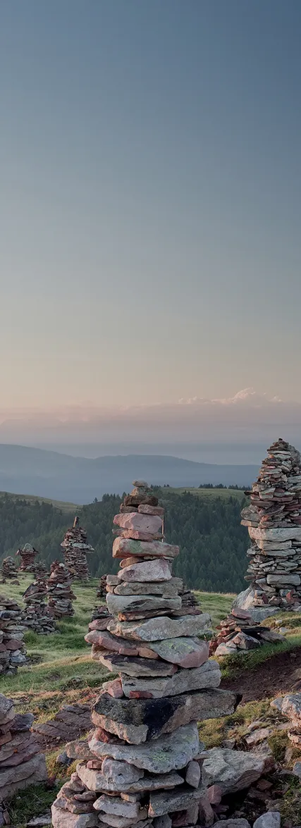 Steinerne Mandler auf grüner Bergkuppe in den Südtiroler Alpen bei Abenddämmerung nahe Mölten